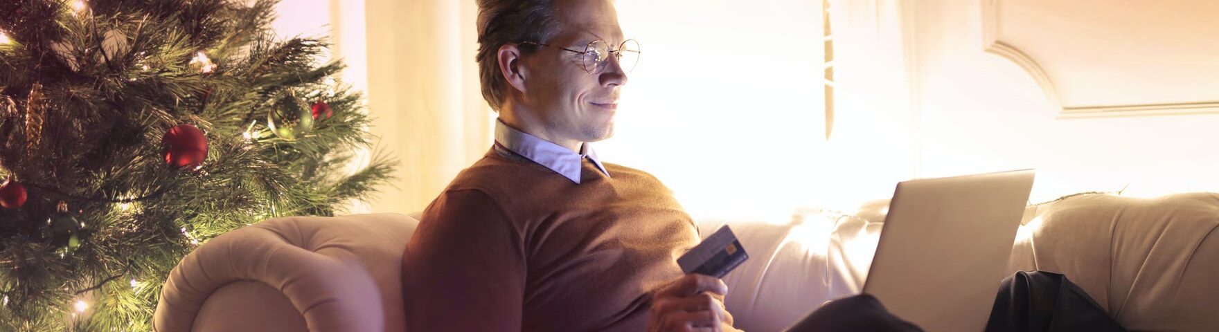 man in brown long sleeve sweater and black pants sitting on brown sofa chair using laptop