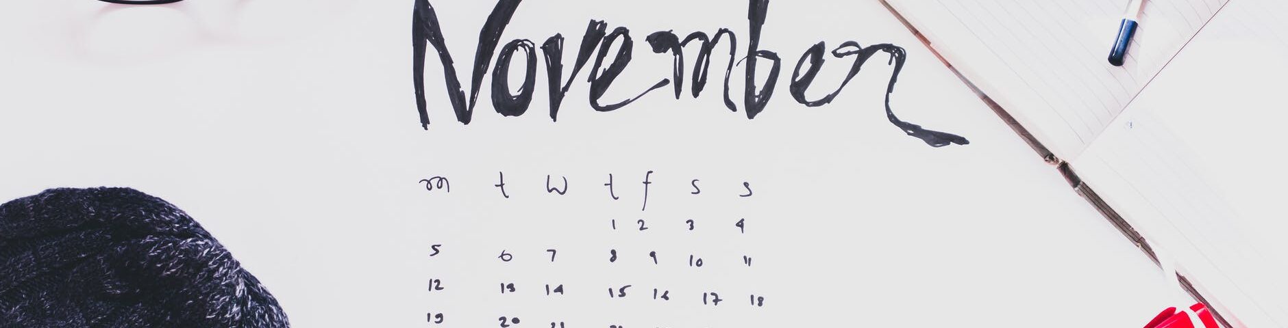 top view of a cup of coffee and and variour other items n top of the november month calender