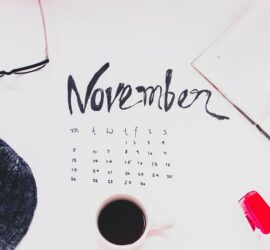 top view of a cup of coffee and and variour other items n top of the november month calender