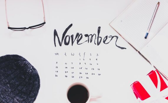 top view of a cup of coffee and and variour other items n top of the november month calender