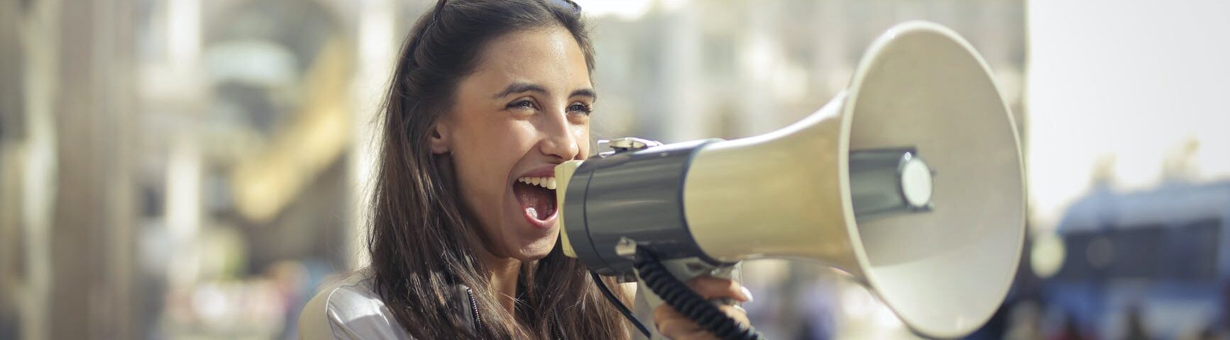 cheerful young woman screaming into megaphone