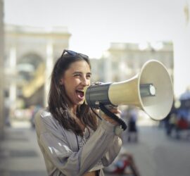 cheerful young woman screaming into megaphone