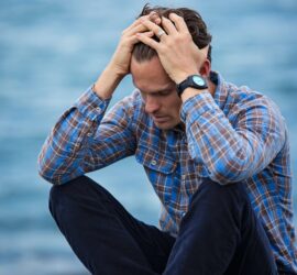 man in blue and brown plaid dress shirt touching his hair