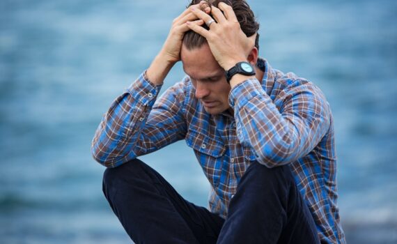 man in blue and brown plaid dress shirt touching his hair