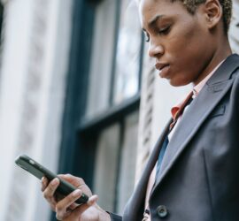crop concentrated ethnic businesswoman with smartphone