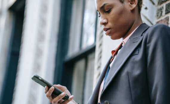 crop concentrated ethnic businesswoman with smartphone
