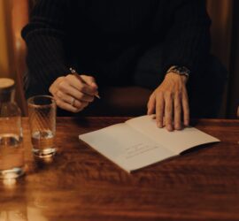 person in black long sleeve shirt holding white paper