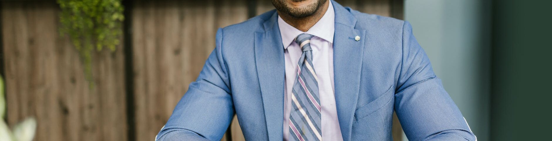 smiling man in blue suit sitting by the table
