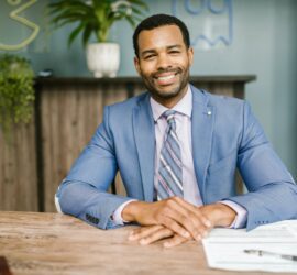 smiling man in blue suit sitting by the table