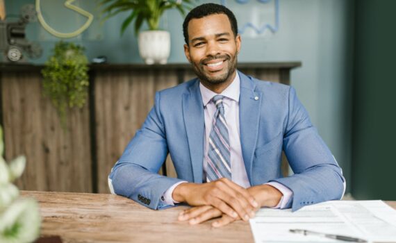 smiling man in blue suit sitting by the table