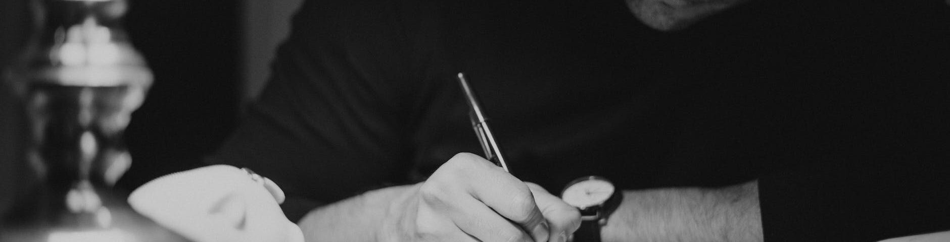 crop man taking notes in copybook in dark home office