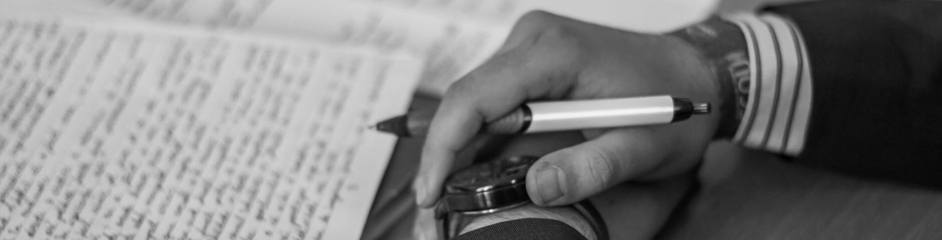 grayscale photography of person holding pen