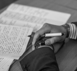 grayscale photography of person holding pen