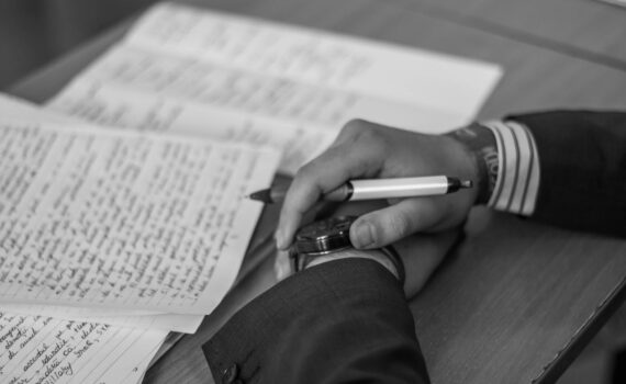 grayscale photography of person holding pen